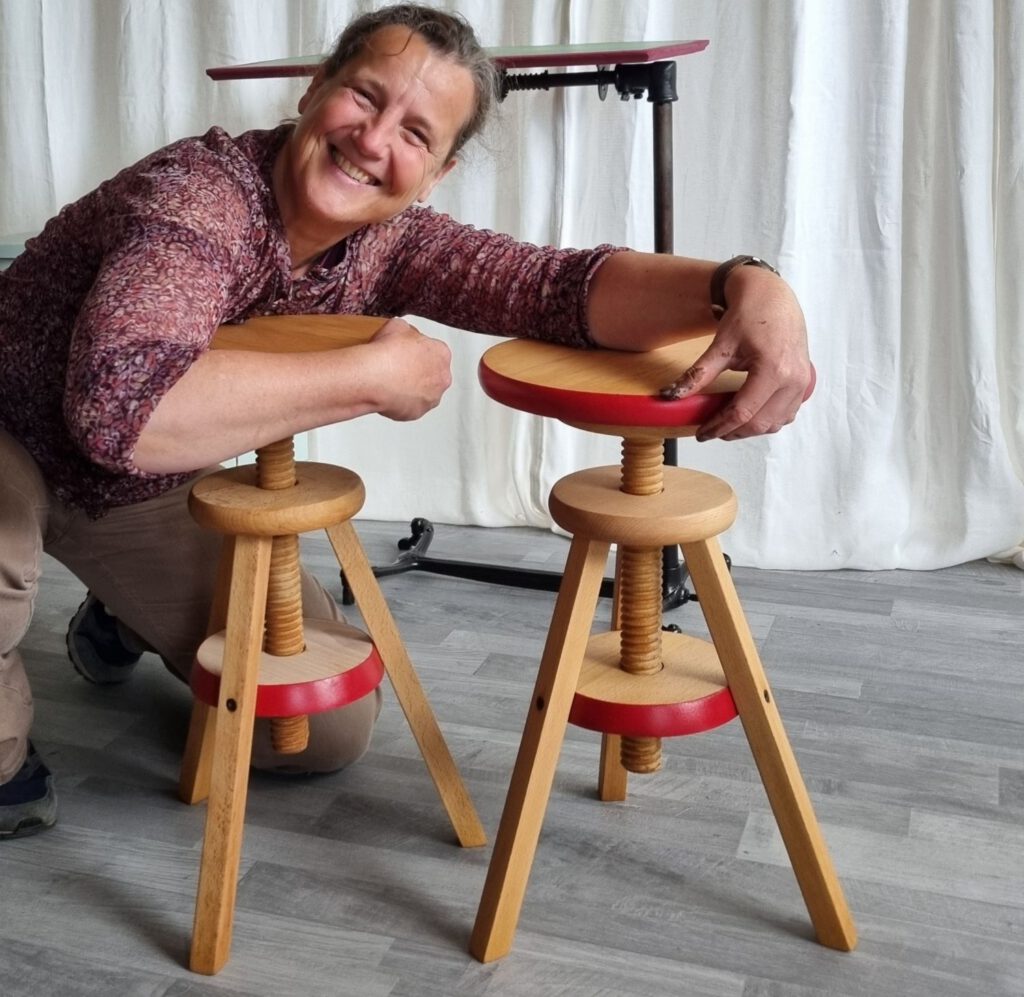 Teilnehmerin mit zwei selbst aufgearbeiteten Holzhockern im TREWIENS Workshop